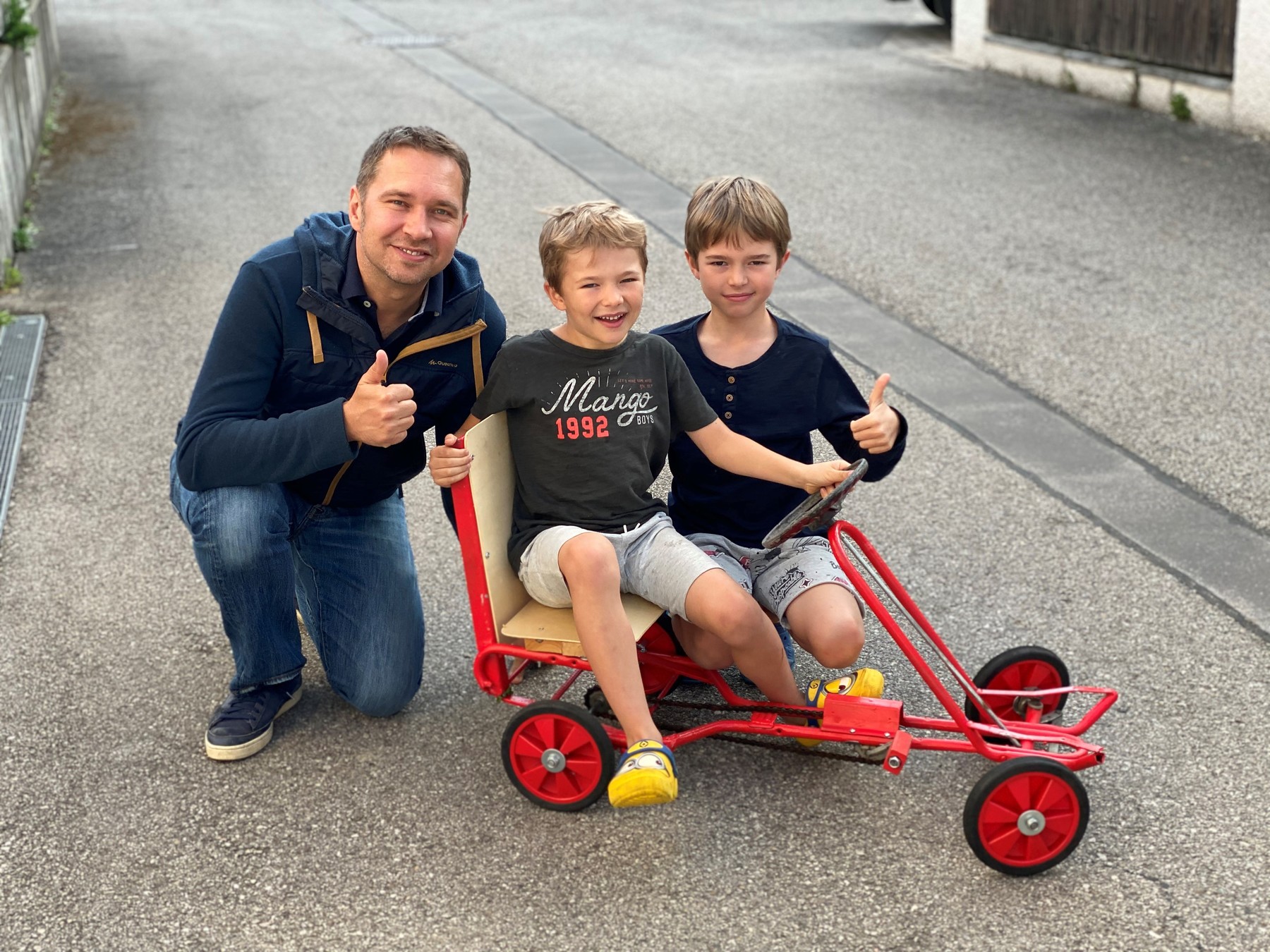 Vater und Söhne präsentieren stolz das fertige Gokart