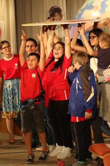Kinder des Nachbarschaftszentrums 'Sale für Alle' überbringen eine selbst gebastelte Weltkugel-Scheibe